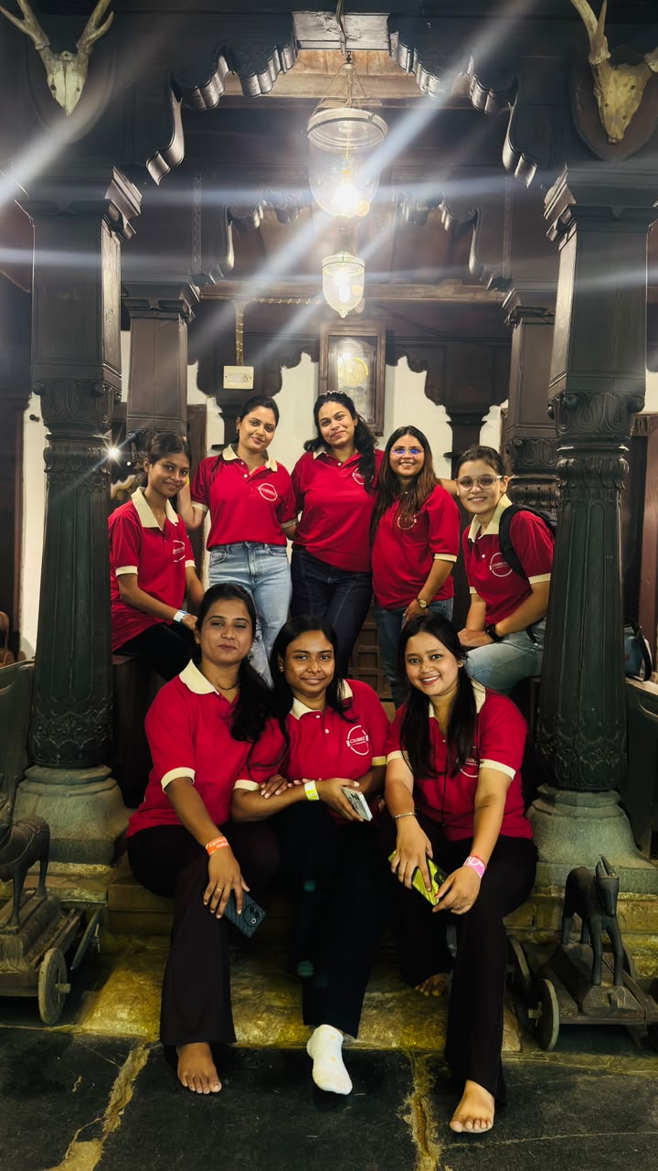 A smiling Cindrebay Nagpur group in red Cindrebay shirts, framed by carved wooden pillars